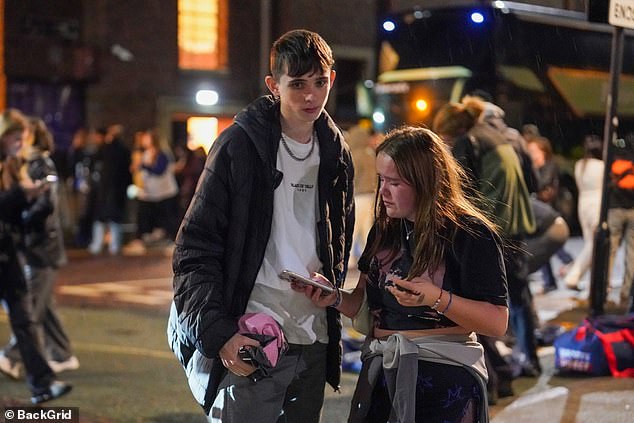 Two dejected young people stand on the street outside the O2 Town Hall in Newcastle