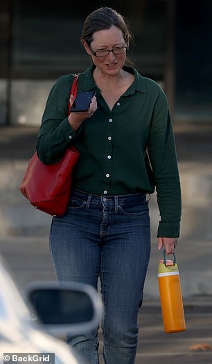 She wore a dark green blouse that was partially unbuttoned around the collar and tucked into the waist of a pair of jeans