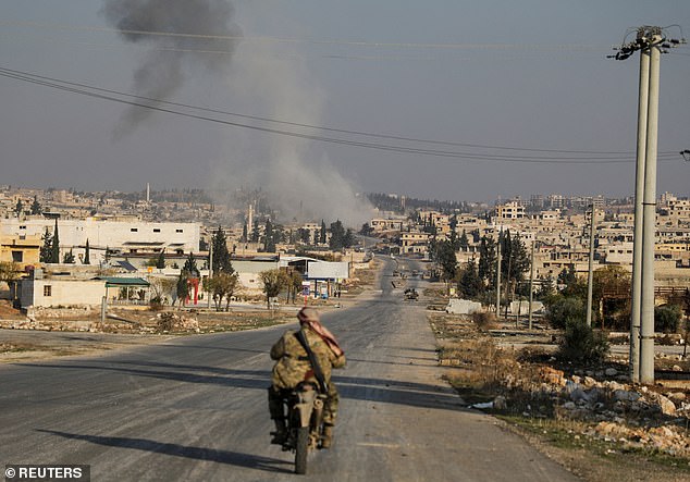 Smoke rises as a member of the rebels led by the Islamic militant group Hayat Tahrir al-Sham rides a motorcycle in al-Rashideen, Aleppo province, Syria, November 29, 2024