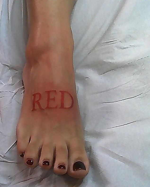 Doja's new tattoo was placed on the top of her right foot and reads 'RED' in large, bold capital letters in the color red