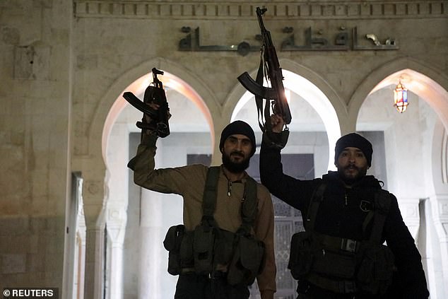 Rebel fighters hold weapons in front of the governor's building of Hama as they gather after Syrian rebels captured the city during their advance through northern Syria