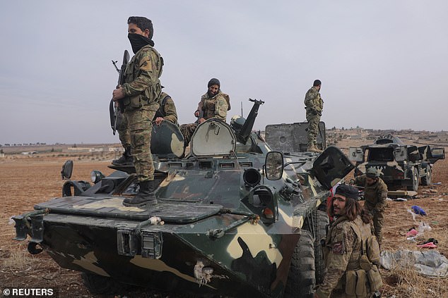 Rebel fighters stand on top of a military vehicle in the Homs countryside after Syrian rebels carried out their lightning advance on Saturday