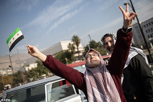 People celebrate in the streets after Syrian rebels captured the city of Damascus, waving rebel flags and cheering