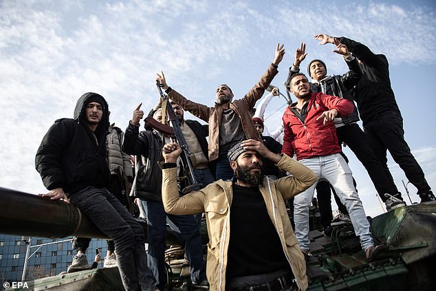 People standing on a tank celebrate after Syrian rebels took over the city of Damascus