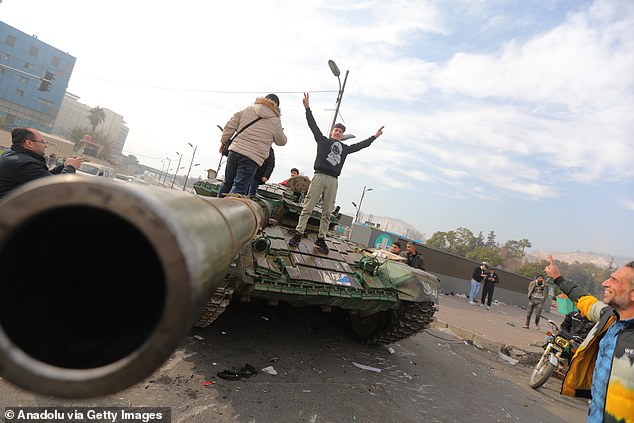 People climbed onto abandoned tanks to celebrate the downfall of the regime