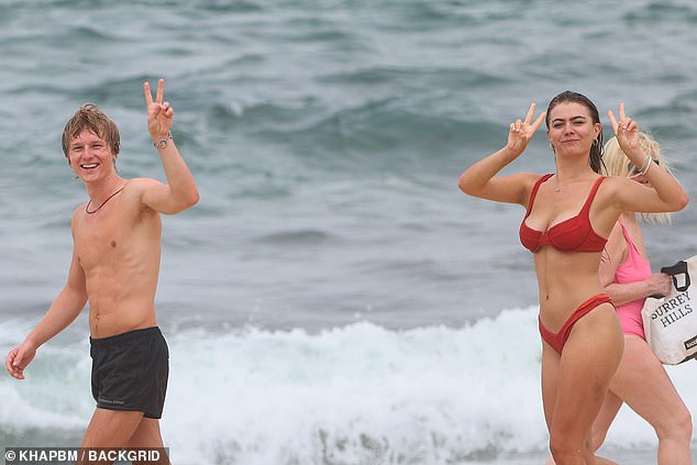 The couple appeared happy and relaxed as they walked down to the water, chatting and smiling as they held up peace signs for photographers