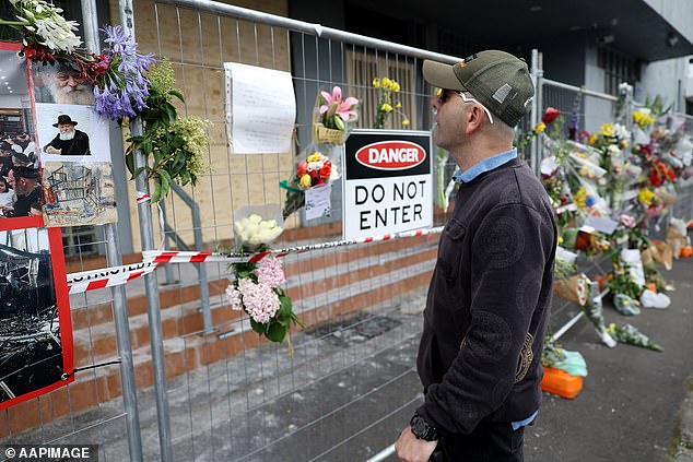 A man is seen reading a message left on the fence of the Adass Israel Synagogue after a firebomb attack