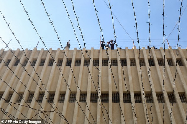 People stand on the roof of Saydnaya prison as Syrian rescuers search for hidden cellars