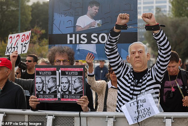 Protesters chant slogans and hold up signs during a rally against Benjamin Netanyahu during his trial on corruption charges at the Tel Aviv District Court