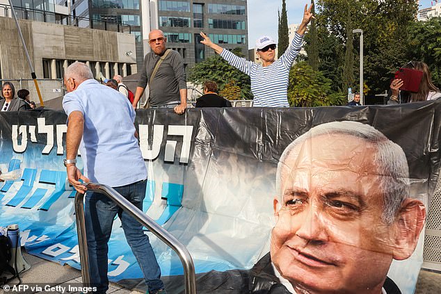 Protesters raise a banner and placards during a rally in support of Israeli Prime Minister Benjamin Netanyahu during his trial on corruption charges