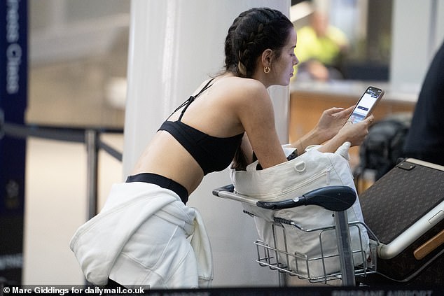 The star scrolled through her phone as she waited to check her bags