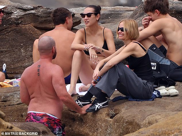 The trio looked relaxed and happy in each other's company as they sat atop some rocks at the beach