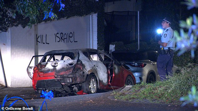 Anti-Semitic graffiti was sprayed on a wall behind a burnt-out car in Woollahra