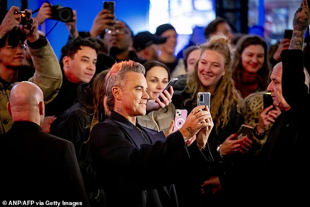 The hitmaker flipped his short, graying locks up as he flashed his smile as he posed for photos ahead of the screening