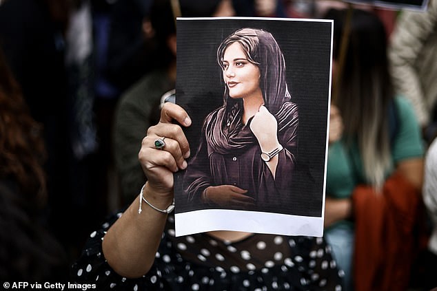 A protester holds a portrait of Mahsa Amini during a demonstration in Brussels. The law comes two years after protests rocked Iran following the death in custody of 22-year-old Mahsa Amini