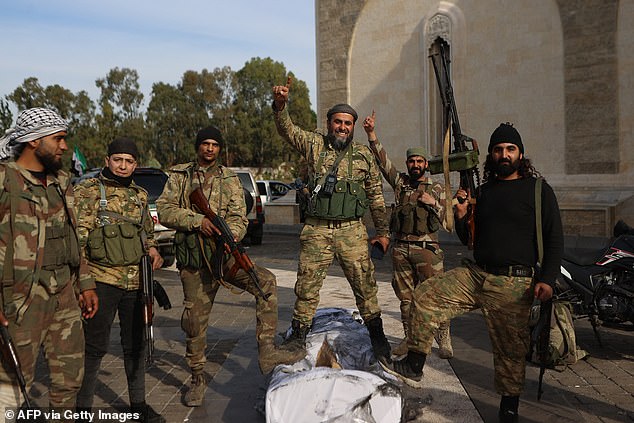 Rebel fighters pose for a photo outside the mausoleum of late Syrian President Hafez al-Assad in the family's ancestral village of Qardaha