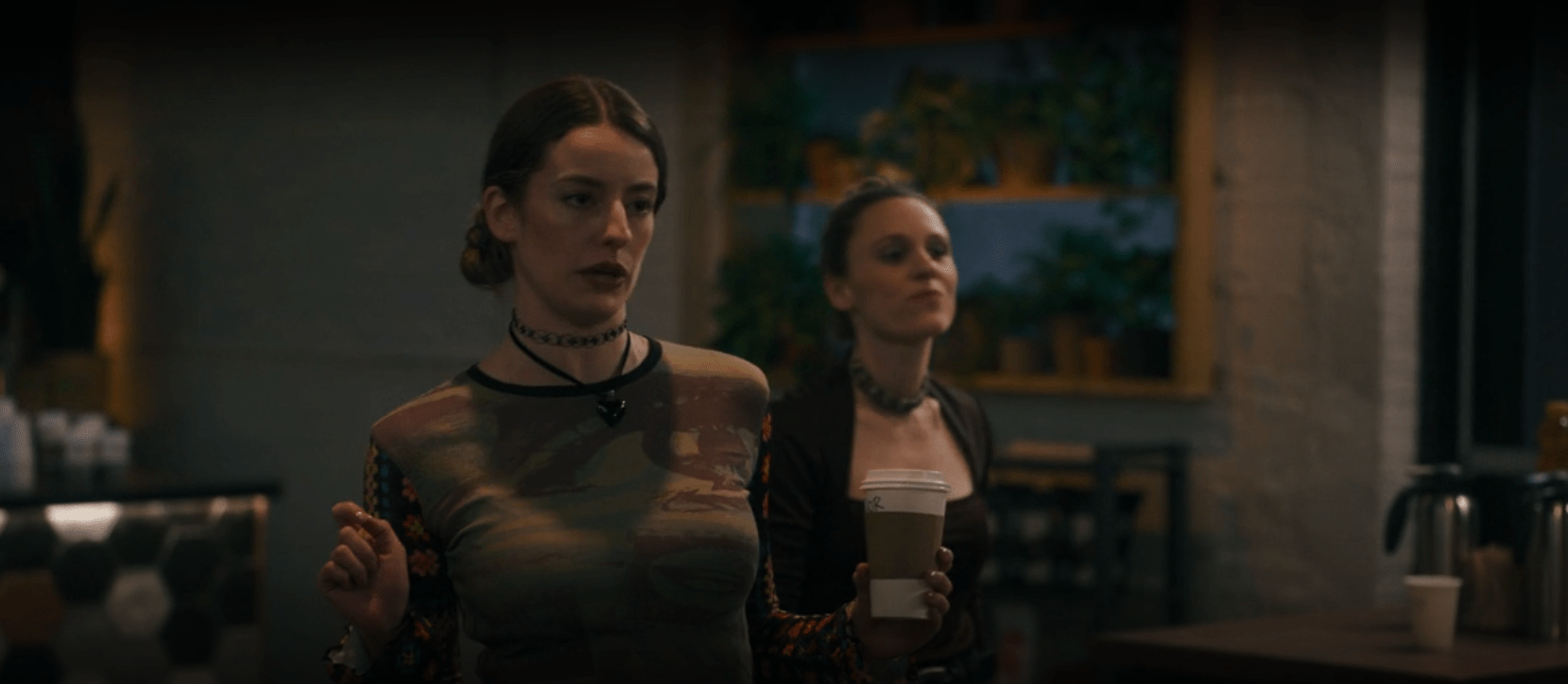 Two women look jaded as one of them holds a coffee cup in What We Do in the Shadows