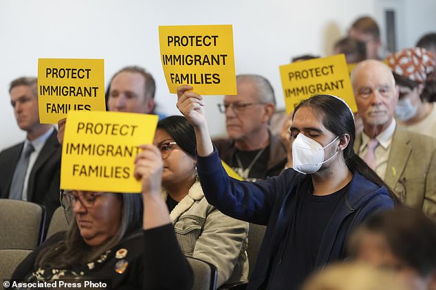 People hold signs during a San Diego County Board of Supervisors meeting on Tuesday, December 10, 2024 in San Diego