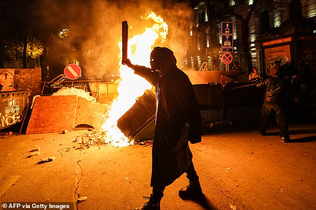 Protesters light a fire at the foot of a makeshift barricade erected on a Tbilisi street early December 1, 2024, during demonstrations against the government's decision to postpone talks on European Union membership during a post-EU crisis elections.