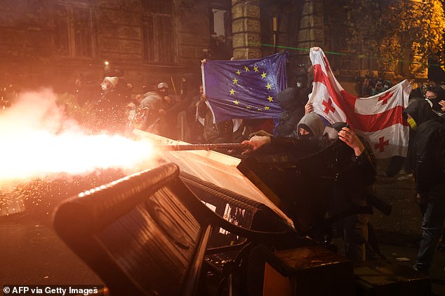 Protesters carrying Georgian and European flags clash with police during a demonstration against the government's decision to postpone talks on European Union membership during a post-election crisis, in Tbilisi, early December 1, 2024