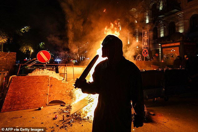 Protesters light a fire at the foot of a makeshift barricade erected on a Tbilisi street during demonstrations against the government's decision to postpone European Union membership talks