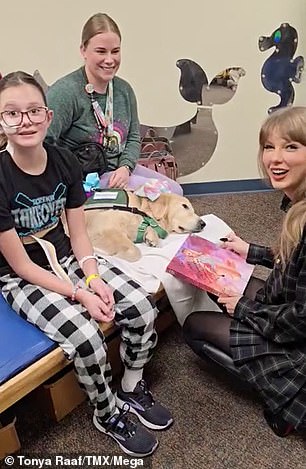 Swift smiles at the camera as she signs some memorabilia for a young girl