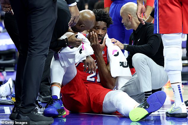 Embiid is attended to by medical personnel before leaving the arena for further medical evaluation