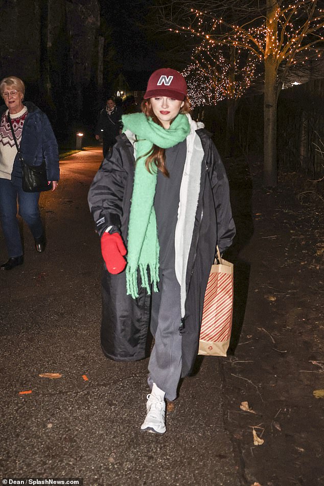 Maisie is further equipped with a thick green scarf, a red baseball cap and a pair of matching red gloves