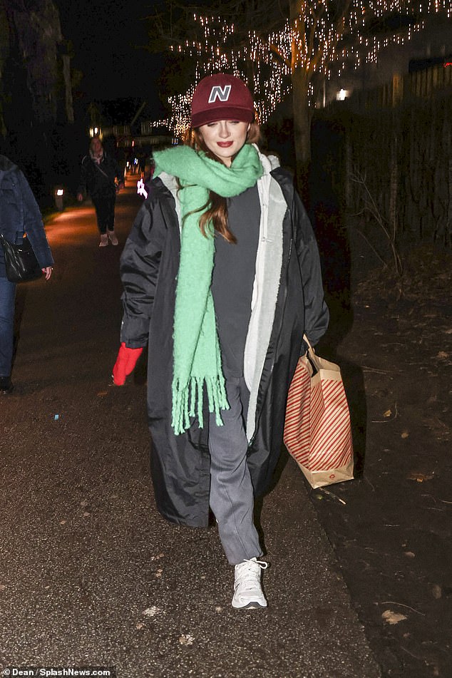 Maisie is further equipped with a thick green scarf, a red baseball cap and a pair of matching red gloves