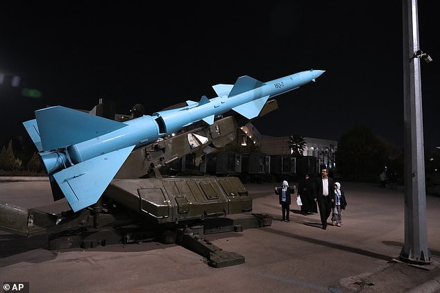 People walk past an Iranian domestically built rocket as they visit the Revolutionary Guards National Aerospace Park outside Tehran, Iran, on November 15 this year.