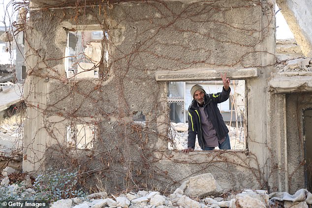 A man leans through the window frame of a destroyed building on December 14 in Jobar, Syria