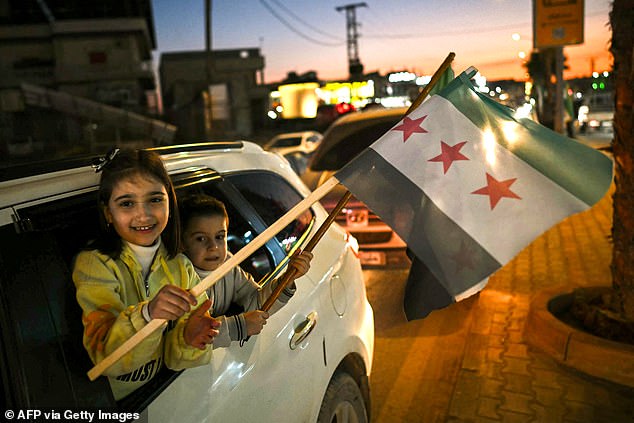 Children waving the Syrian independence-era flag in the town of al-Dana, near Sarmada, in Syria's northern Idlib province on December 13