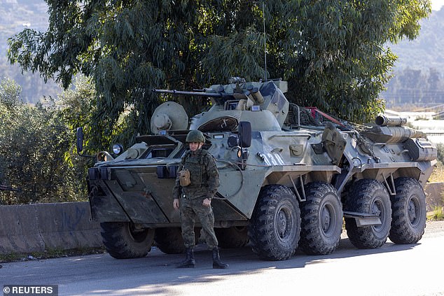 A Russian soldier in a military convoy stands by the road due to an engine failure as they travel through the Hmeimim air base on the Syrian coast in Latakia, Syria, on December 14, amid reports that Russia is now withdrawing its assets from the country