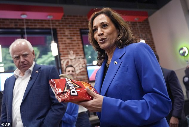 Vice President Kamala Harris holds a bag of Doritos chips as Democratic vice presidential candidate Minnesota Governor Tim Walz looks on at the Sheetz supermarket during a campaign stop