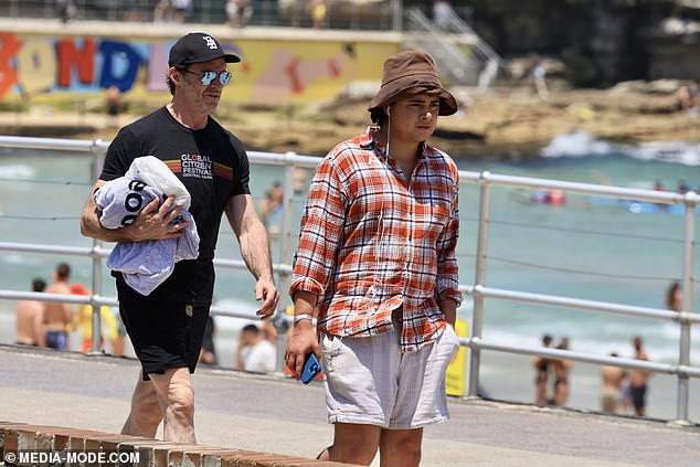 The actor's son listened to music as they walked along Bondi Beach