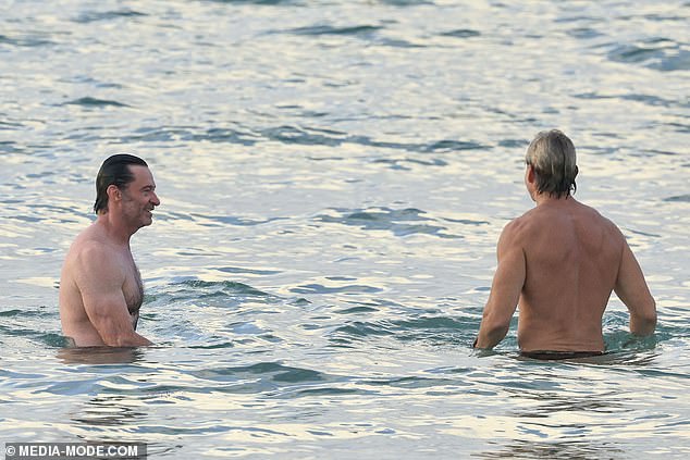 Hugh was seen laughing as he chatted with his friend while relaxing in the ocean