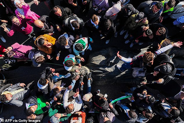 An aerial view shows protesters dragging a toppled statue of late President Hafez al-Assad across the street during a student rally near the campus of Damascus University in the Syrian capital on December 15, 2024