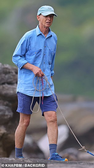 Serious stood aloof as he strolled his small dog through the quiet streets and along a rocky beach path