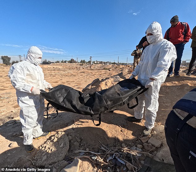 Teams work on the uncovered mass grave believed to contain the remains of civilians killed by the ousted Assad regime