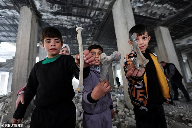 Children hold bones of various shapes found in the Tadamon district, littered with remains after what residents and rights groups described as years of killings there under the rule of Syria's Bashar al-Assad.