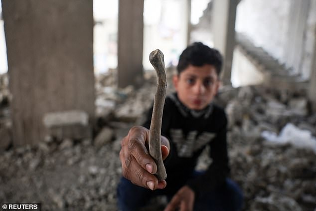 A Syrian child holds a human bone while playing in Tadamon district