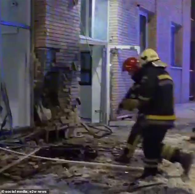 Emergency services rush into the apartment building after the explosion and look down at the electric scooter