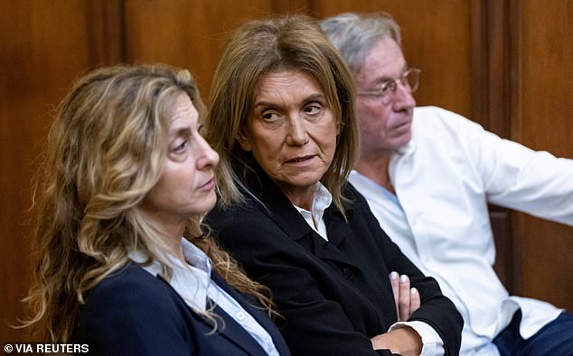 Shlomy and Orly Alexander (center and right), the parents of a TV broker and his identical twin brother accused of rape, urged their sons to smile during a preliminary court hearing