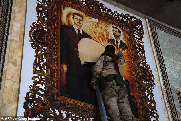 An anti-regime fighter tears off a poster depicting Syrian President Bachar al-Assad (L) and his brother Maher at the airport of the northern Syrian city of Aleppo on December 2, 2024