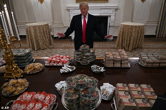 Trump poses with a table full of fast food in the White House State Dining Room in January 2019 ahead of a reception with the Clemson Tigers