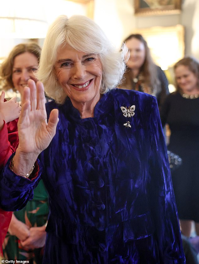 Queen Camilla waves and speaks to a young girl as she welcomes children and families to Clarence House on December 12