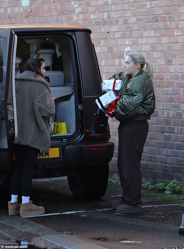 The reality star, 25, cut a nonchalant figure as she precariously balanced piles of Christmas presents to give to staff at her offices