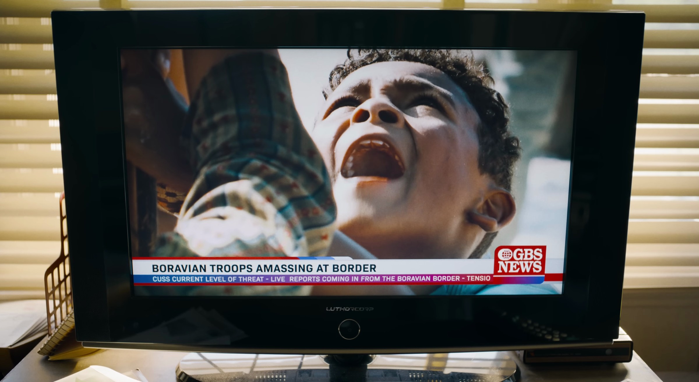 A child shouts at a TV with a chyron saying that Boravian forces have gathered at the border in Superman 2025