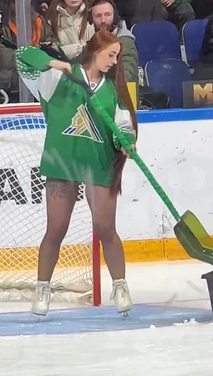 The ice girl cleans around the goal post