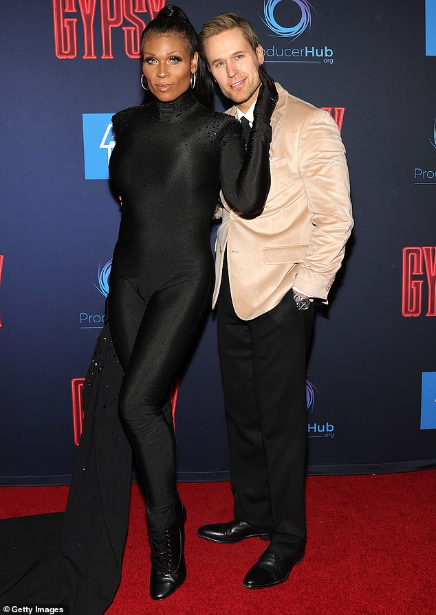 RuPaul's Drag Race alum Peppermint cut a scene-stealing figure in a skin-tight black jumpsuit as she struck a provocative pose with younger actor Dan Amboyer